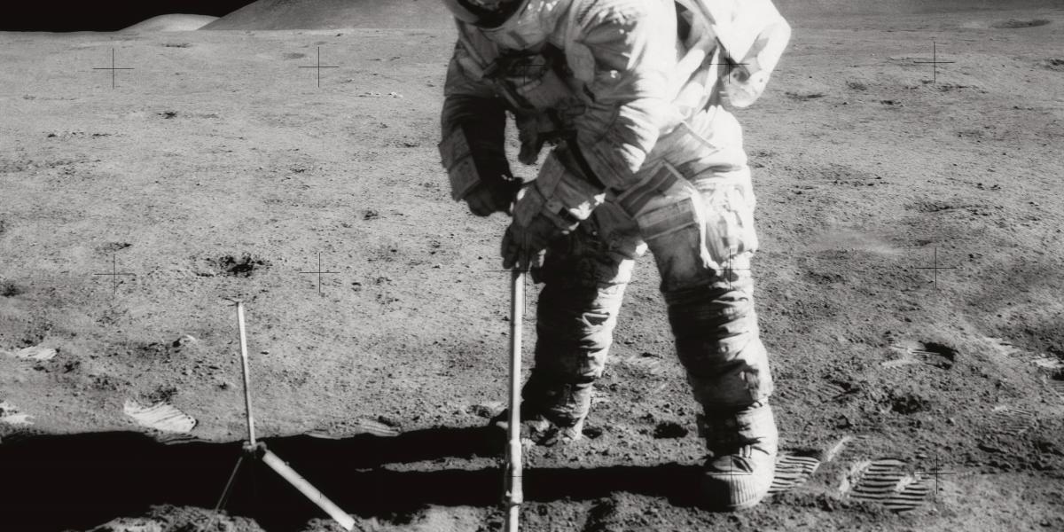 A black and white image of James Irwin digging into the lunar soil during Apollo 15 mission