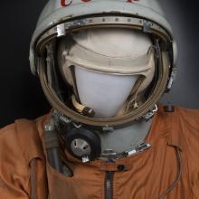 A helmet with CCCP on it, on a mannequin in a white suit.