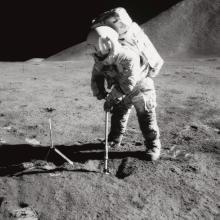 A black and white image of James Irwin digging into the lunar soil during Apollo 15 mission