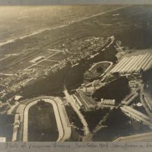 Black and White aerial photograph of city, elliptical race track in lower left corner