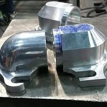 One rough milled aluminum elbow (left) in contrast to one hand shaped and polished elbow (right).