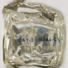 A metal package with a blue sticker and "Day 3 Meal C" on the outside.