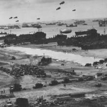 Zepplin shaped balloons float over tanks and more on a D-Day battlefield. 