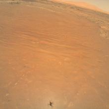 An image of the orange surface of Mars seen from the perspective of the Ingenuity helicopter.