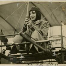 A woman flying a biplane. 