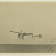 black and white photo. One-half left rear view of monoplane several feet off the ground.  Handwritten text in lower right corner.