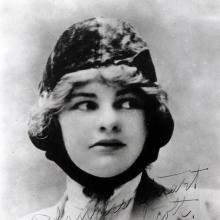 A women in a pilot's cap looks to the right. 