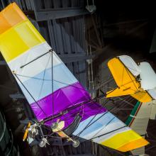 View of the undercarriage of a glider. The wing fabric is multi-colored.