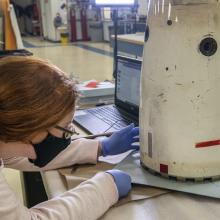 A woman examines a metal object. 