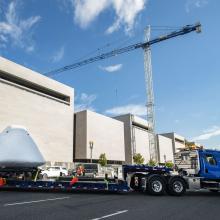 Command module Columbia at the back of a big truck with the National Air and Space Museum in the background.