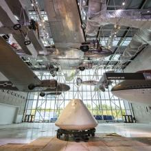 Command module Columbia sits in the middle of a museum gallery and surrounded by exhibits.