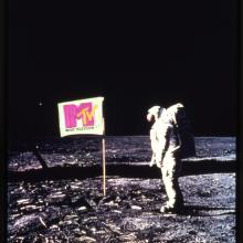 A photo of an astronaut on the Moon standing next to a flag with the MTV logo on it.