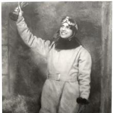 A woman in a flying suit raises her hand in the air.