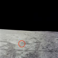 A photo of the surface of the Moon with a red circle around a small circular object, which is a golf ball.