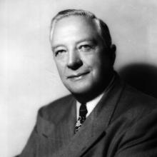 Thomas Braniff poses for a picture wearing a suit with his arms folded.