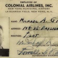 Small black and white card. Text on top: Employee of Colonial Airlines, inc. Headshot photo of a man on right side. He has dark hair and is holding a dark clapboard that reads "EW 45." On the right column are name, address, position: pilot, and two signatures: Michael A. Gitt on top and Lowell S. Harding on bottom.