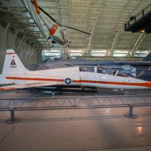 View of a white and orange painted airplane in the museum hanger.