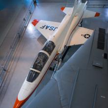 Overhead view of a white and orange painted airplane in the museum hangar.