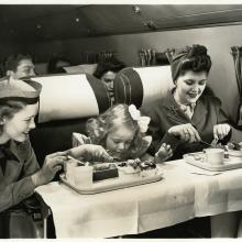 United Airlines flight attendant assisting passengers wearing the United Airlines flight attendant cap (1946)