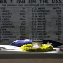 The remains of retired Master Chief Glenn Harvey Lane sit on a table at the USS Arizona Memorial with names written on a wall in the background.