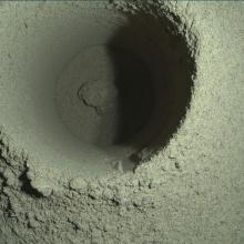 A circular hole in the soil of Mars with smooth sides indicating it was created by a mechanical instrument.