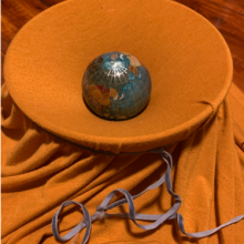 A blanket draped over a bowl, with a ball made to look like Earth perched on top.