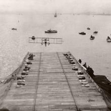 A ramp over water with a biplane approaching it.