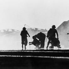 A silhouette of individuals next to a fighter jet