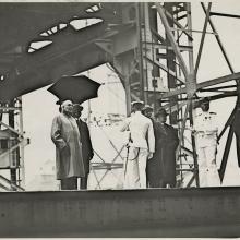 Black and white grainy image of people standing by a steel structure