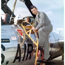 US Air Force Major Robert C. Mikesh poses standing on access ladder of Martin B-57B Canberra on the ground at Griffiss Air Force Base