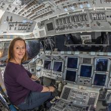 Curator Jennifer Levasseur sits in the cockpit of Space Shuttle Discovery.