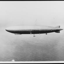 An airship is seen flying above the ocean.