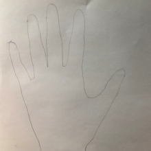 A drawing of an outline of a hand on paper. 