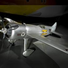 A silver colored, small monoplane featuring a yellow decal on the side that says Champion.