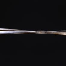 A wooden propeller against a black background. The right side of the propeller is very damaged, and the entire propeller has a split through it.