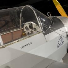 A side view of front half of a gray colored prop plane. Written under the cockpit window is "experimental."