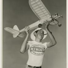 A teenaged-looking boy holds up a large model airplane as if he is about to launch it into the air.