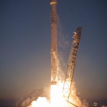 A rocket launching. You can see a stand that was holding it lean away to the left, and the fire of the launch below. 