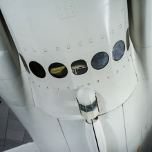 The white cylindrical body of a plane with seven round windows at the bottom.