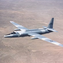 A grey-blue camouflaged plane in flight. 