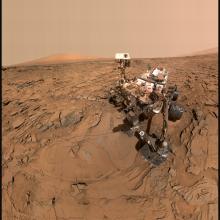 A rover takes a photograph on the orange, dusty martian surface. 