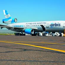 A DC-10 jet airliner parked on an airport runway. It is covered in the orbis logo and says flying eye hospital on the side.