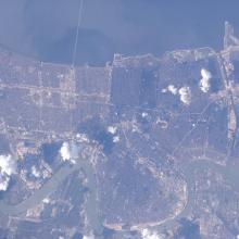 A satellite image of New Orleans. Puffs of smoke rise from the ground.