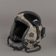 A flying helmet covered in camouflage and various wires.