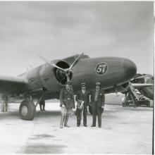 One-half right front view of the Boeing 247D with three men posing in front.