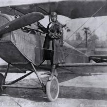 A woman stands on the wing of an airplane.