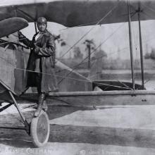 A woman stands on the wing of an airplane.