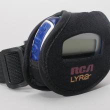 A small circular speaker, which looks similar to a digital watch, in a pouch with a strap.