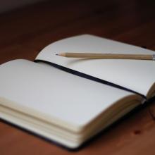 A blank open journal with a pencil on top. 