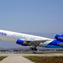 A plane taking off that reads "Orbis, Flying Eye Hospital, orbis.org" on the side. 